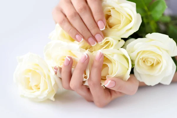 一个有着美丽的法国指甲和白玫瑰的女人的手 — 图库照片