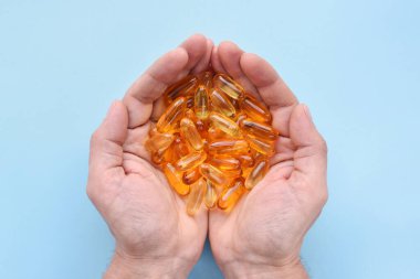 Mavi arka planda kapsüllerde bulunan Omega 3 vitamini balık yağı. Üst görünüm