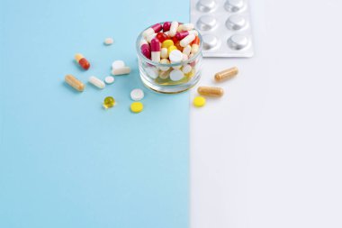 Mavi ve beyaz arka planda çeşitli ilaç hapları, haplar ve kapsüller. Metnin için boşluk