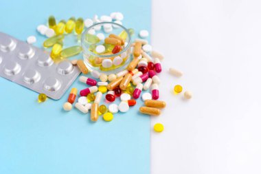 Mavi ve beyaz arka planda çeşitli ilaç hapları, haplar ve kapsüller. Metnin için boşluk