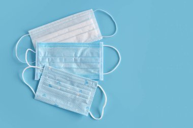 Mavi arka planda tıbbi maskeler. Ağız ve burnu örtmek için tipik 3 katlı cerrahi maske. Bakterilerin prosedür maskesi. Sağlık ve Koruma Konsepti.