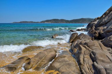 Taşları ve şeffaf mavi suyu olan güzel bir deniz manzarası.