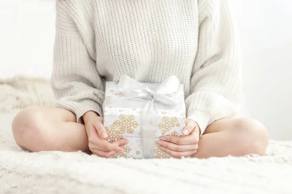 Girl sits on the bed and holding a gift — Stock Photo, Image