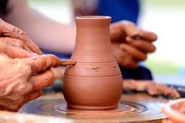Potter çömlek çarkında seramik demlik yapıyor.
