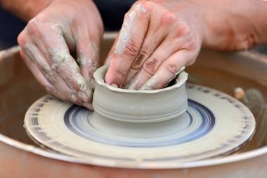 Potter çömlek çarkında seramik demlik yapıyor.