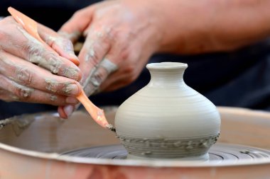 Potter çömlek çarkında seramik demlik yapıyor.