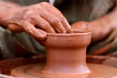Potter çömlek çarkında seramik demlik yapıyor.