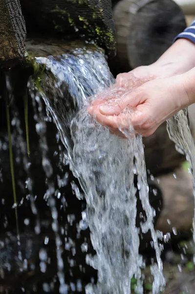 Agua vertiendo en la mano de la mujer — Foto de Stock