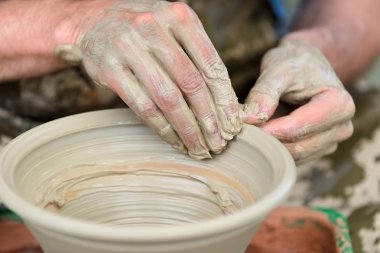 Potter çömlek çarkında seramik demlik yapıyor.