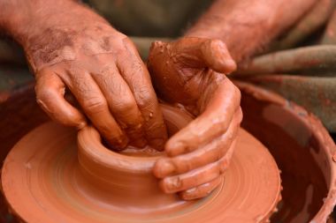 Potter çömlek çarkında seramik demlik yapıyor.