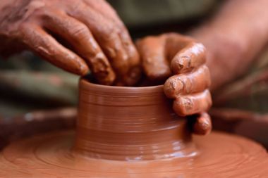 Potter çömlek çarkında seramik demlik yapıyor.