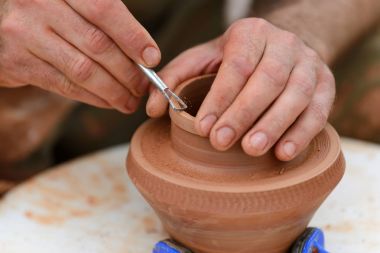 Potter çömlek çarkında seramik demlik yapıyor.