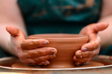 Potter çömlek çarkında seramik demlik yapıyor.