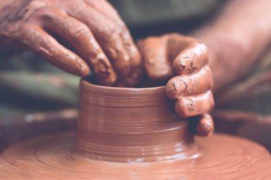 Potter çömlek çarkında seramik demlik yapıyor.