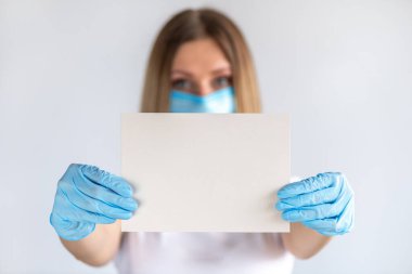 Genç hemşire ya da doktor elinde fotokopi alanı olan boş tabela gösteriyor. Bir kağıt parçasına odaklan. Beyaz arka plandaki kadın