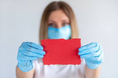 Genç hemşire ya da doktor elinde fotokopi alanı olan boş bir tabela gösteriyor. Bir kağıt parçasına odaklan. Beyaz arka plandaki kadın