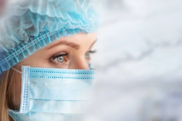 Surgical Nurse or doctor with face mask and cap. Health care, surgery. Close up portrait of young caucasian woman model on white background