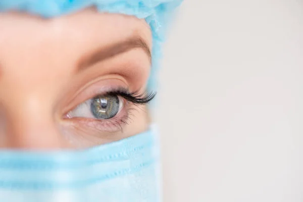 Nurse or doctor with face mask and cap. Health care, surgery. Close up portrait of young caucasian woman model on white background