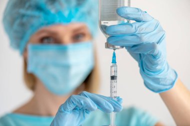 Hemşire eline enjeksiyon için şişe ve şırınga. Aşı için tıbbi cam şişe. Bilim ekipmanları, sıvı ilaç ya da aşı. Tıp konsepti