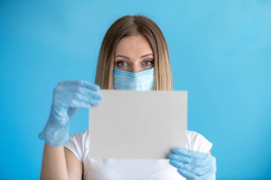 Genç hemşire ya da doktor elinde fotokopi alanı olan boş tabela gösteriyor. Modele odaklan. Mavi arka plandaki kadın