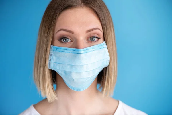 Nurse or doctor with face mask. Health care, surgery. Close up portrait of young caucasian woman model on blue background