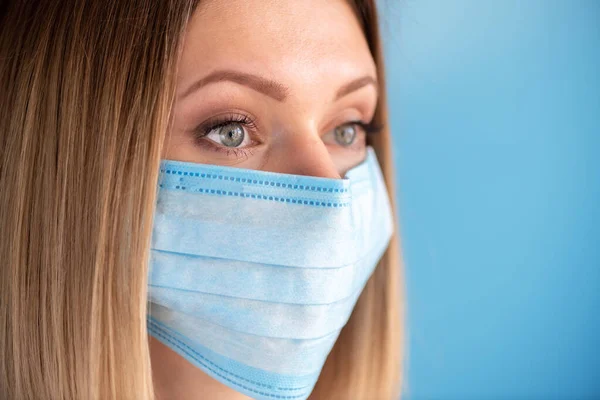 Nurse or doctor with face mask. Health care, surgery. Close up portrait of young caucasian woman model on blue background
