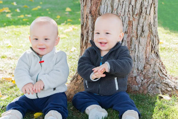 Twin Toddlers sentado perto da árvore tronco — Fotografia de Stock