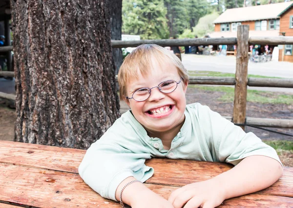 Liten pojke med Downs-syndrom sitter vid bord — Stockfoto