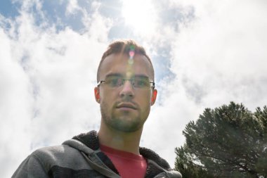 Genç adam güneş ışığı kamerayla bakarak genel gider