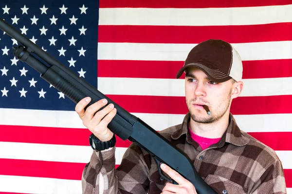 Joven sosteniendo pistola en fondo de bandera americana —  Fotos de Stock