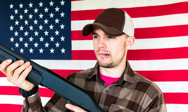 Молода людина тримає пістолет на фоні американський прапор — стокове фото
