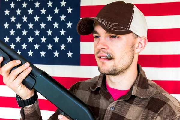 Homem jovem segurando arma no fundo da bandeira americana — Fotografia de Stock