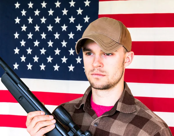 Ung Man hålla pistolen på amerikanska flaggan bakgrund — Stockfoto