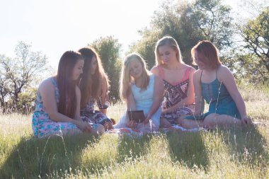 Çimenli alan güneş ışığı yükü ile birlikte oturan kızlar