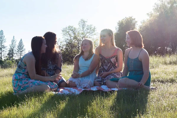 Ragazze sedute insieme in campo erboso con luce solare in testa — Foto Stock