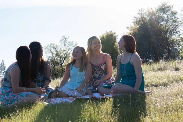 Mädchen sitzen zusammen auf einer Wiese mit Sonnenlicht über Kopf — Stockfoto