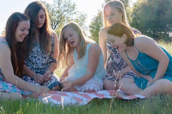 Mädchen sitzen zusammen auf einer Wiese mit Sonnenlicht über Kopf — Stockfoto