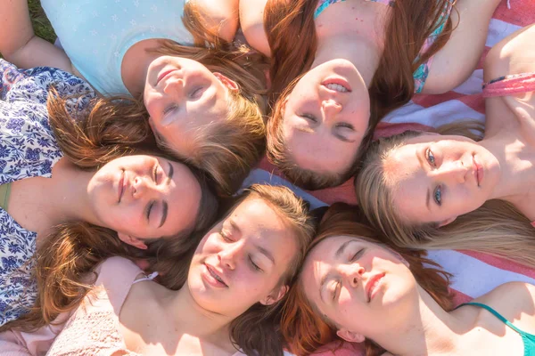 Ragazze sdraiate a terra guardando in alto, alcune con gli occhi chiusi — Foto Stock