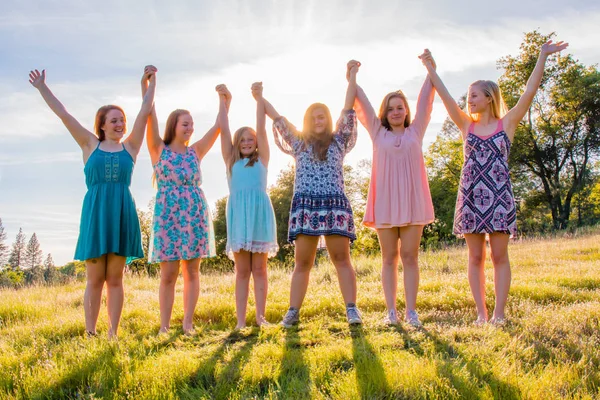 Ragazze in piedi con le braccia sollevate e la luce del sole in testa — Foto Stock