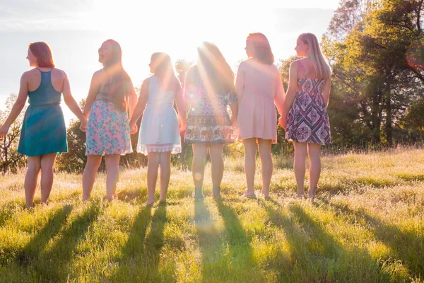 Meninas em pé juntos de frente para o pôr do sol brilhante — Fotografia de Stock