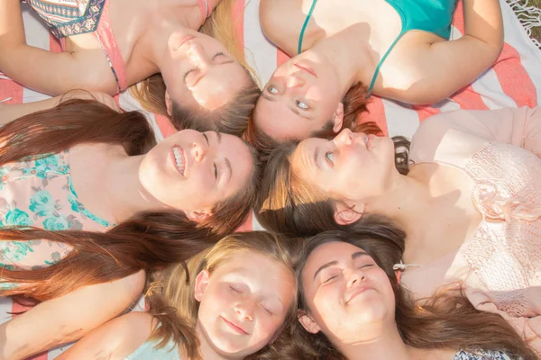 Chicas acostadas en el suelo mirando hacia arriba, algunas con los ojos cerrados Imagen de stock