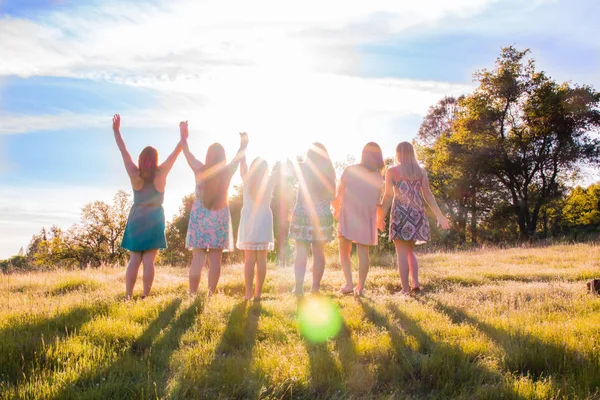 Niñas de pie con los brazos levantados y la luz del sol por encima Imagen de archivo