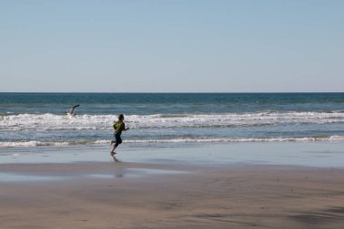 Kumsalda koşan genç kız.