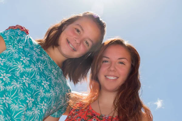 Deux filles avec le ciel bleu et la lumière du soleil en arrière-plan — Photo