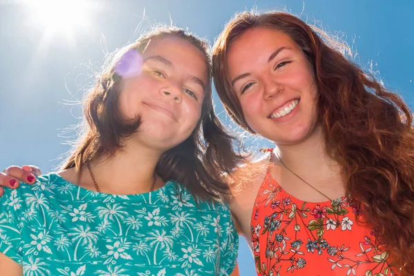 Deux filles avec le ciel bleu et la lumière du soleil en arrière-plan — Photo