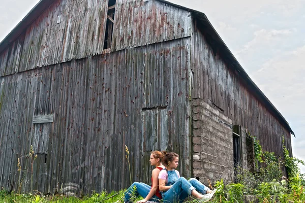 Girls Sitting Near Tall Old Gray Barn — Stock Photo, Image