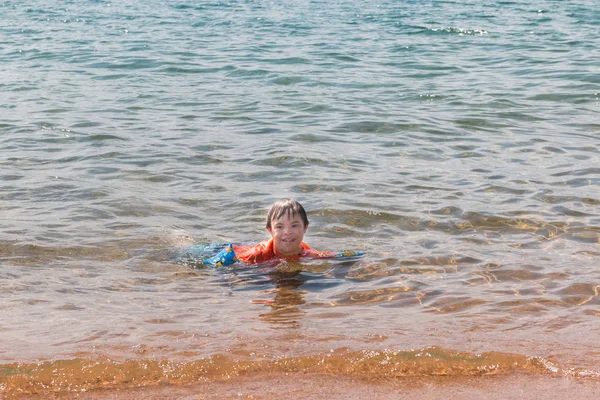 Мальчик с синдромом Дауна в воде на пляже — стоковое фото