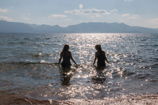 Silhouette di due giovani ragazze in acqua — Foto Stock