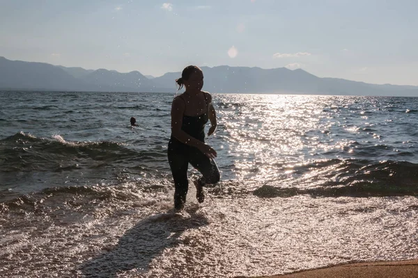 Silhouette di una ragazza che corre attraverso le onde — Foto Stock