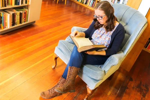 Jeune fille lisant un livre à la bibliothèque — Photo